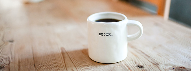 White coffee mug on table with word 'begin' on mug